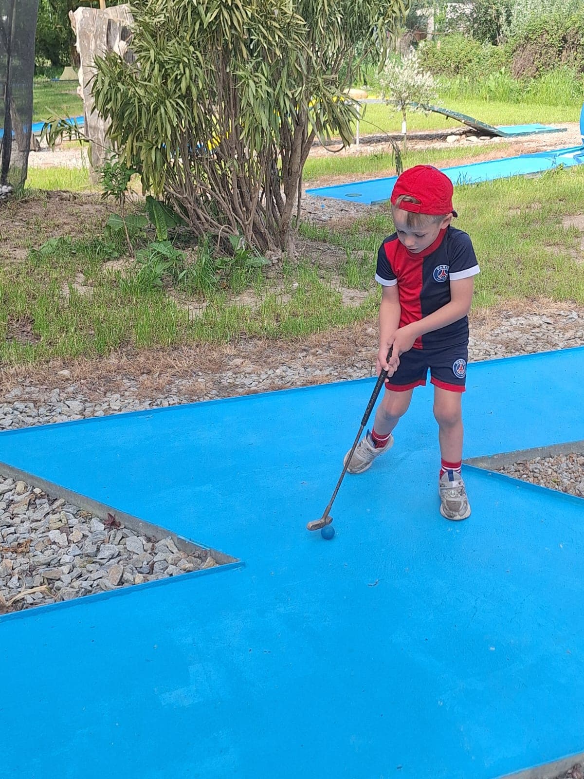 Enfant jouant au mini-golf sur le parcours bleu